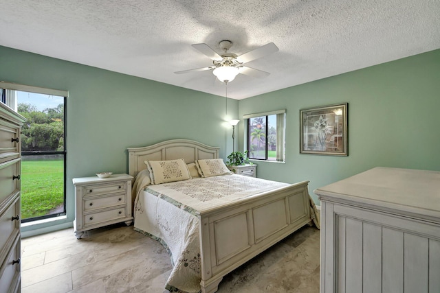 bedroom featuring a textured ceiling, multiple windows, and ceiling fan