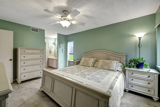 bedroom with a textured ceiling, connected bathroom, and ceiling fan