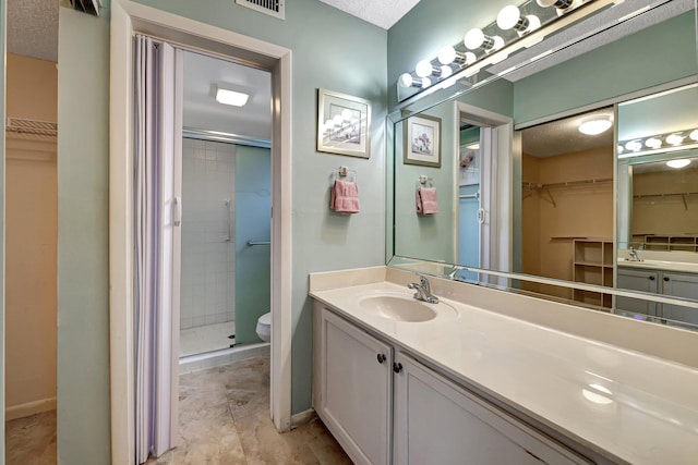 bathroom with vanity, a textured ceiling, toilet, and a shower with shower door