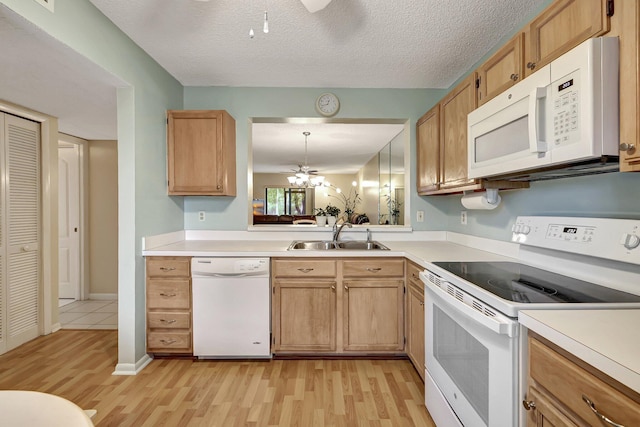 kitchen with white appliances, sink, a textured ceiling, decorative light fixtures, and light hardwood / wood-style floors