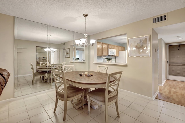 dining space with light tile patterned floors, a textured ceiling, and a chandelier