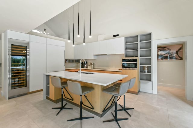 kitchen with a kitchen breakfast bar, sink, a chandelier, white cabinetry, and an island with sink