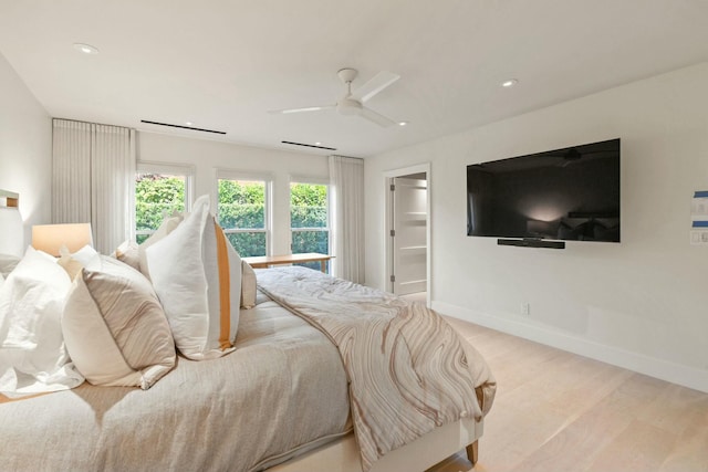 bedroom with light wood-type flooring, a spacious closet, and ceiling fan