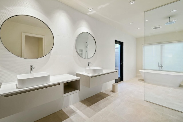 bathroom with a tub to relax in, tile patterned floors, and vanity