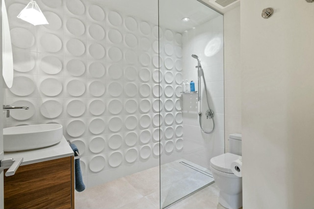 bathroom featuring vanity, tile patterned floors, toilet, walk in shower, and tile walls