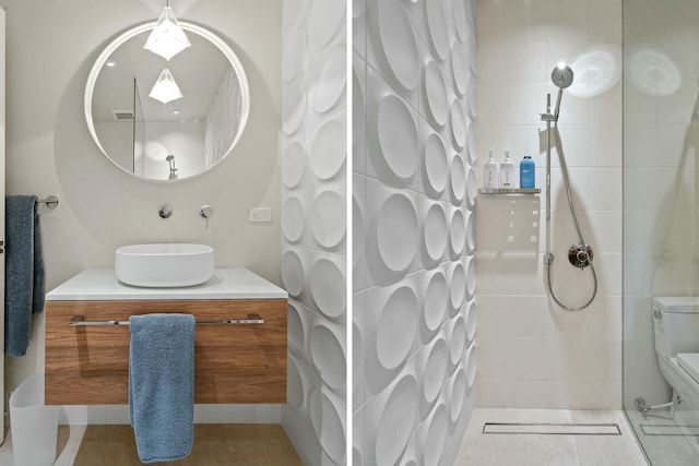 bathroom featuring tile patterned flooring, vanity, toilet, and tiled shower