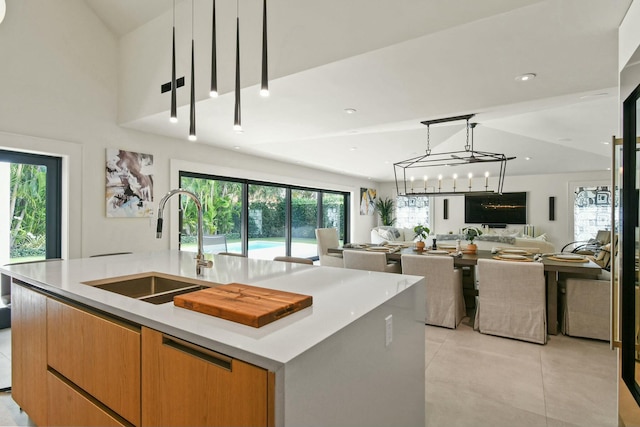 kitchen featuring decorative light fixtures, sink, a large island with sink, and a chandelier