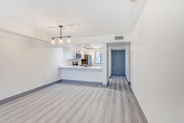 unfurnished living room featuring a textured ceiling, light hardwood / wood-style floors, and sink