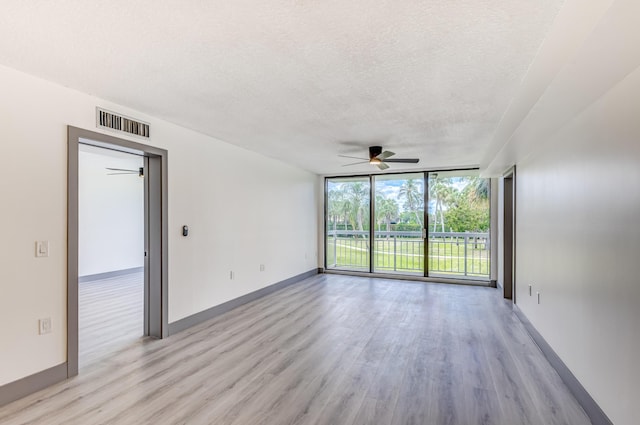 spare room with floor to ceiling windows, ceiling fan, light hardwood / wood-style floors, and a textured ceiling