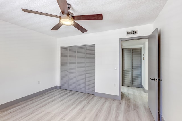 unfurnished bedroom with a textured ceiling, light wood-type flooring, a closet, and ceiling fan