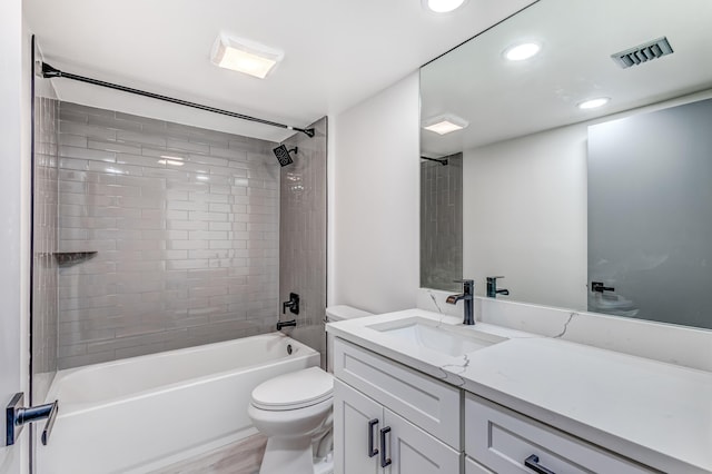 full bathroom featuring hardwood / wood-style floors, tiled shower / bath combo, toilet, and vanity