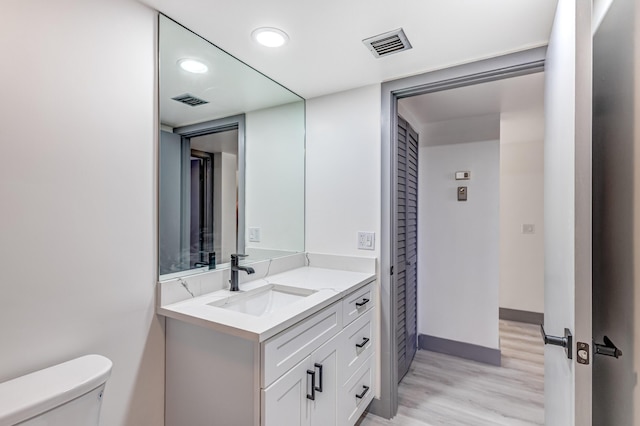 bathroom with vanity, wood-type flooring, and toilet