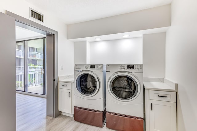 laundry area with cabinets, separate washer and dryer, and light hardwood / wood-style flooring