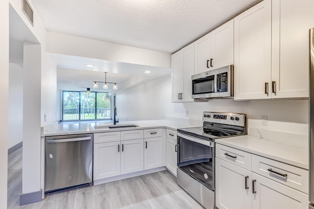 kitchen with sink, white cabinetry, a textured ceiling, and appliances with stainless steel finishes