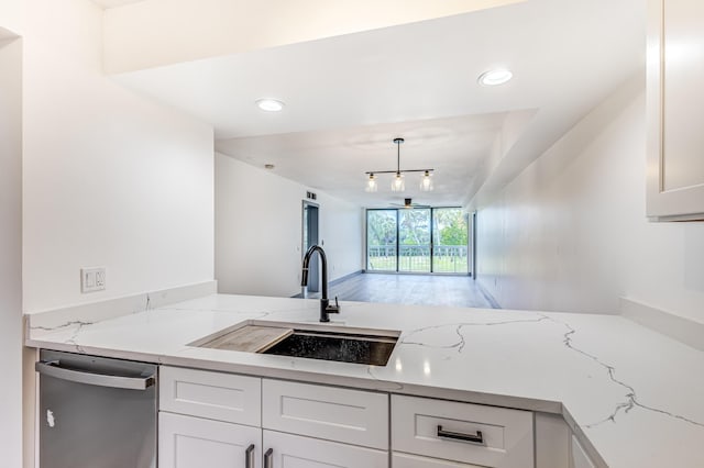 kitchen featuring white cabinetry, light stone countertops, sink, dishwasher, and hanging light fixtures