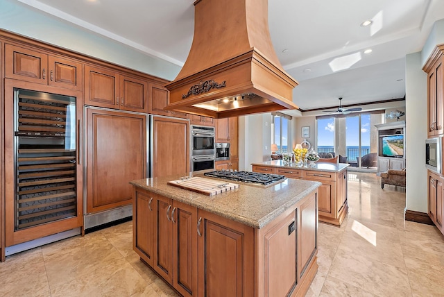 5310 N Ocean Dr Unit Ph-1201, Singer Island, FL 33404 - kitchen featuring light stone counters, a kitchen island, stainless steel appliances, wine cooler, and open floor plan