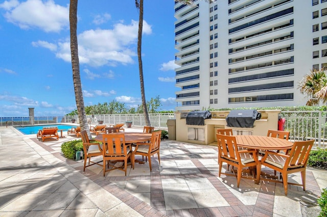 5310 N Ocean Dr Unit Ph-1201, Singer Island, FL 33404 - view of patio / terrace with outdoor dining space, fence, an outdoor kitchen, a community pool, and a grill