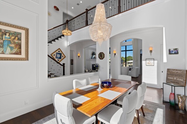 dining space featuring dark hardwood / wood-style floors, a high ceiling, and an inviting chandelier