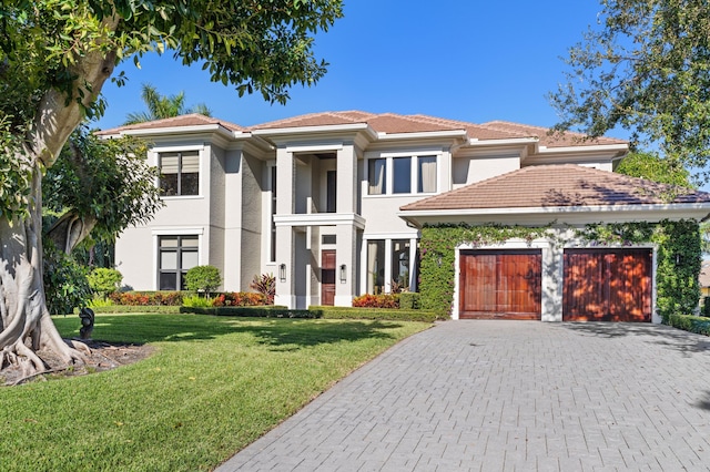 view of front of house with an attached garage, a tile roof, decorative driveway, and a front yard