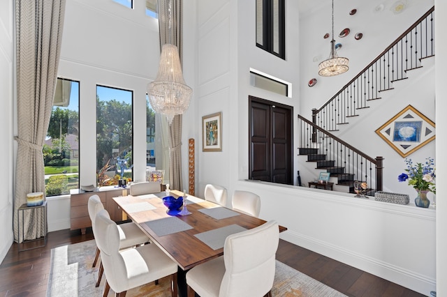 dining area with a towering ceiling, a chandelier, and dark hardwood / wood-style floors