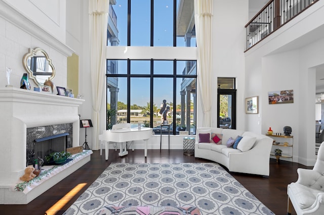 living room with a fireplace, a towering ceiling, and dark wood-type flooring