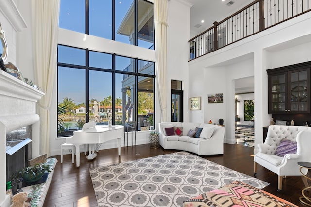 living room with a fireplace, a towering ceiling, and dark wood-type flooring