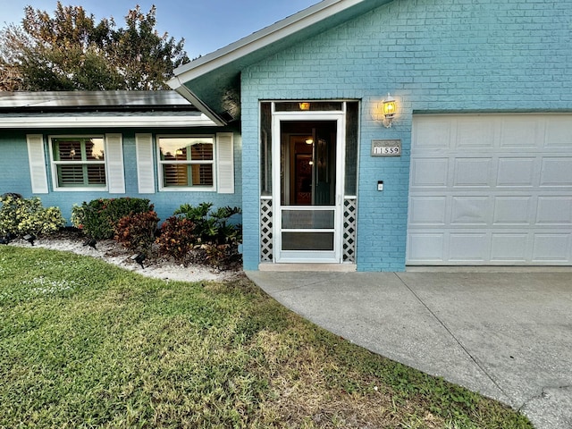 doorway to property featuring solar panels, a lawn, and a garage