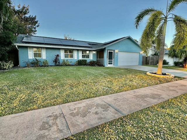 ranch-style house featuring solar panels, a garage, and a front lawn