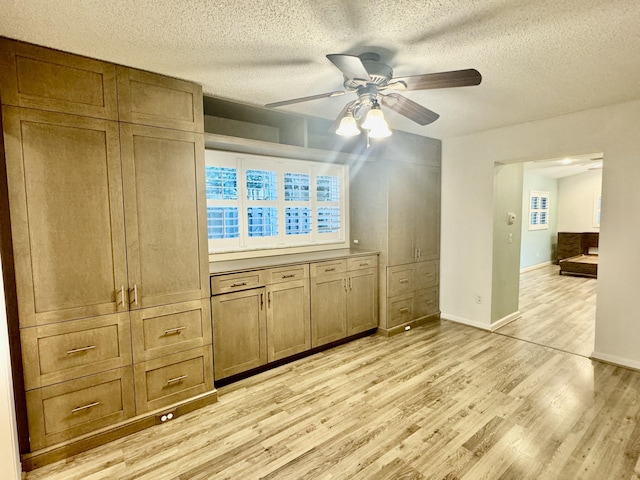 interior space with a textured ceiling, light hardwood / wood-style flooring, and ceiling fan