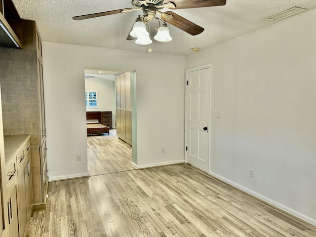 interior space with ceiling fan, light hardwood / wood-style floors, and a textured ceiling