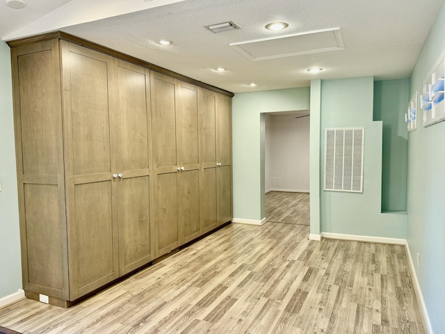 interior space with a textured ceiling, light hardwood / wood-style floors, and a closet