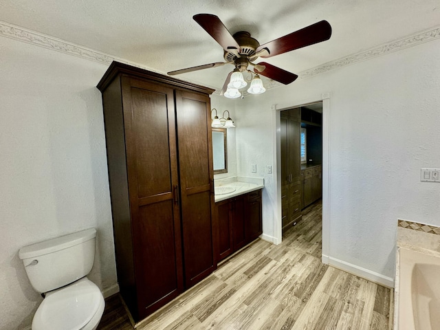 bathroom featuring vanity, ceiling fan, toilet, ornamental molding, and wood-type flooring