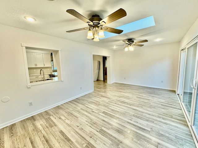 spare room with a textured ceiling, light wood-type flooring, and ceiling fan