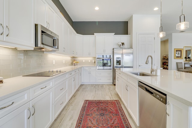 kitchen with white cabinetry, sink, decorative light fixtures, and stainless steel appliances