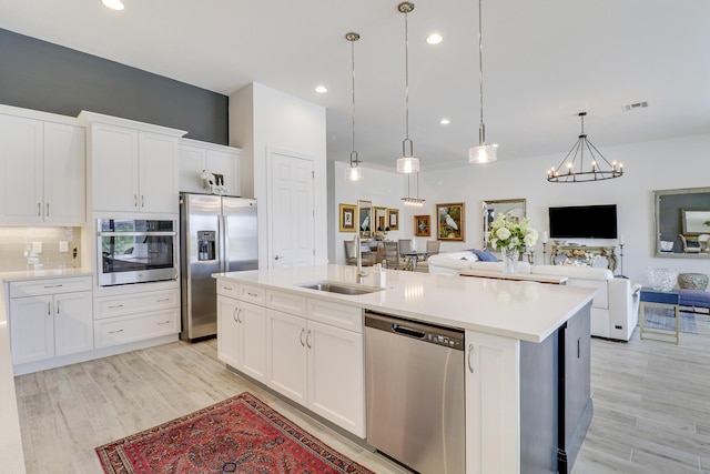 kitchen with white cabinetry, stainless steel appliances, sink, and pendant lighting