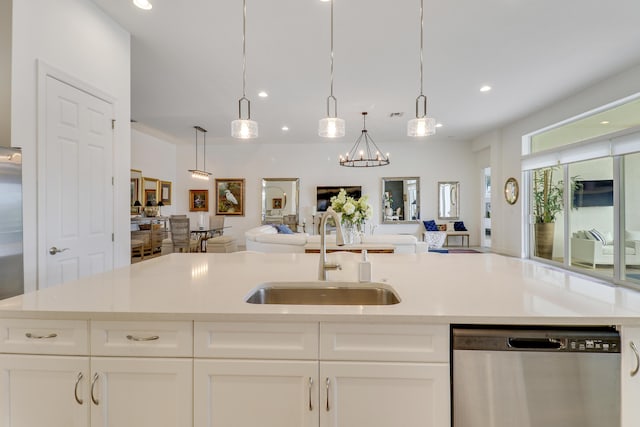 kitchen featuring pendant lighting, white cabinetry, an island with sink, sink, and stainless steel dishwasher