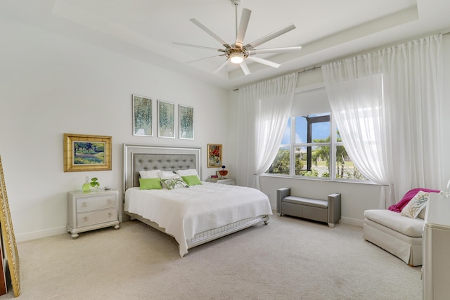 carpeted bedroom featuring ceiling fan and a raised ceiling