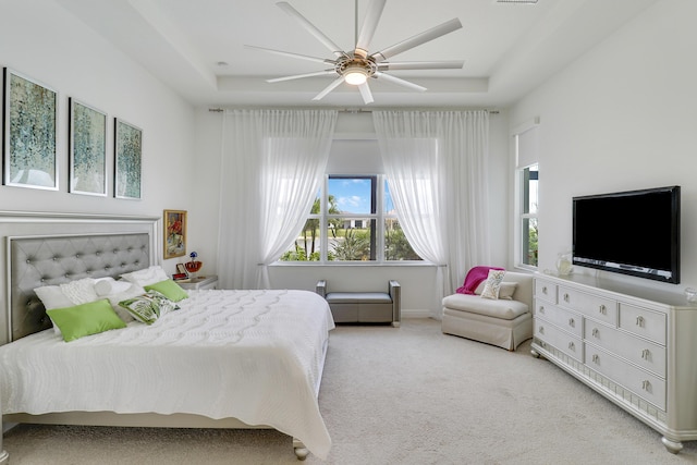 bedroom featuring a tray ceiling, light colored carpet, and ceiling fan