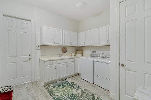 washroom featuring cabinets, sink, washer and dryer, and light wood-type flooring