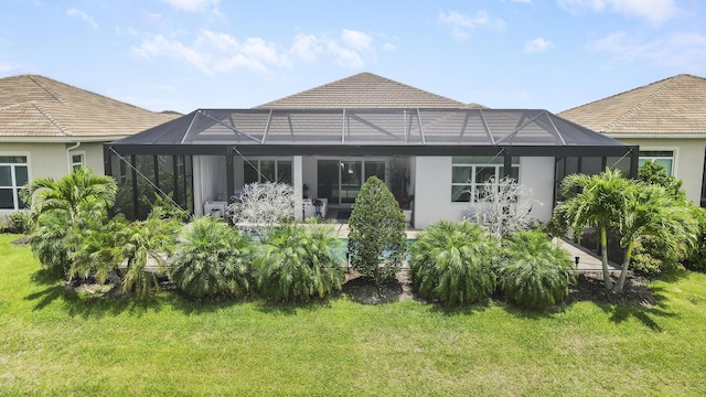 rear view of property featuring glass enclosure and a lawn