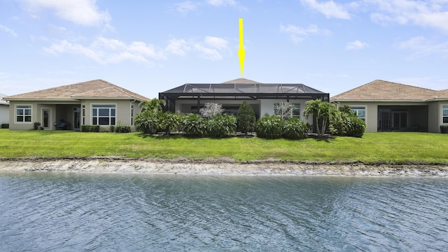 rear view of house with a yard, glass enclosure, and a water view