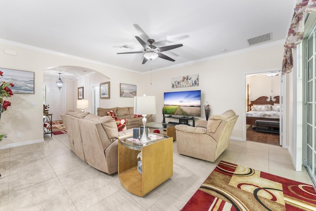 living room featuring arched walkways, light tile patterned floors, visible vents, baseboards, and ornamental molding