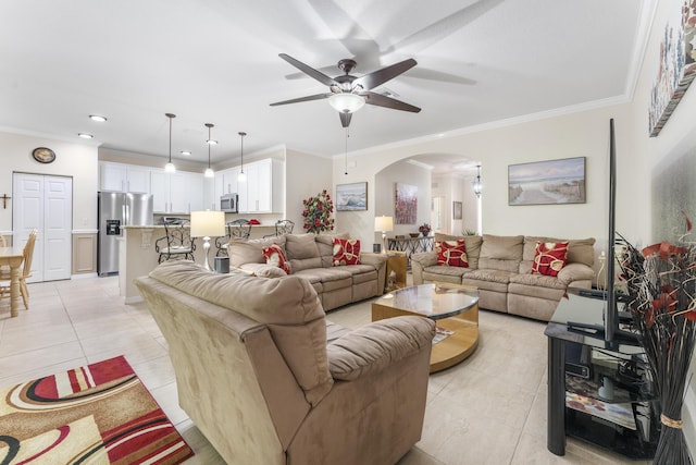 living room with light tile patterned floors, a ceiling fan, arched walkways, and crown molding