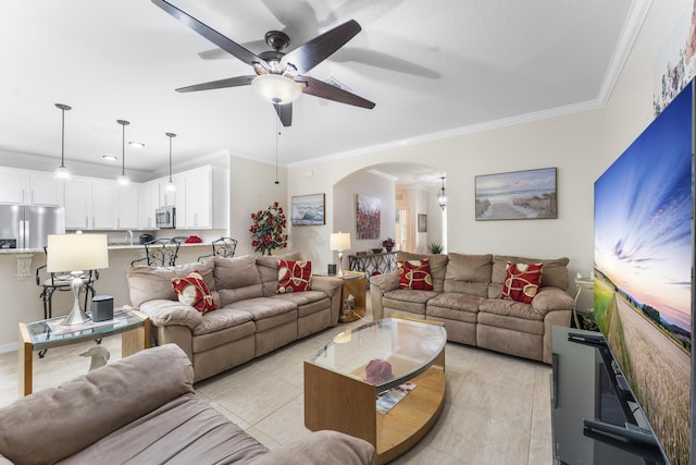 living area with ornamental molding, arched walkways, ceiling fan, and light tile patterned floors