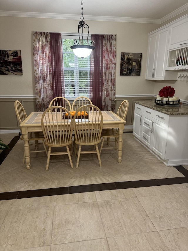 dining space featuring crown molding and wainscoting