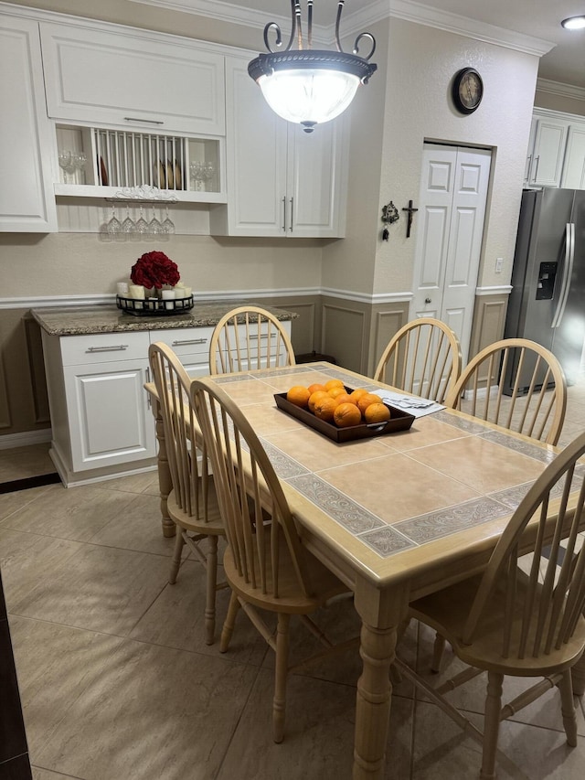 dining space featuring ornamental molding, a decorative wall, and wainscoting