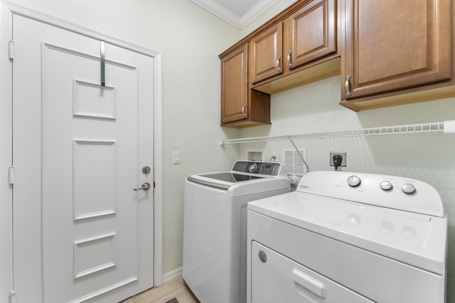 laundry room with cabinet space, crown molding, and separate washer and dryer