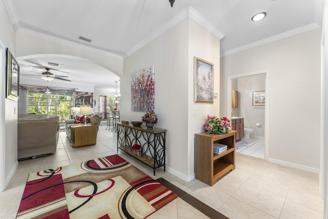 hallway with arched walkways, visible vents, crown molding, and baseboards