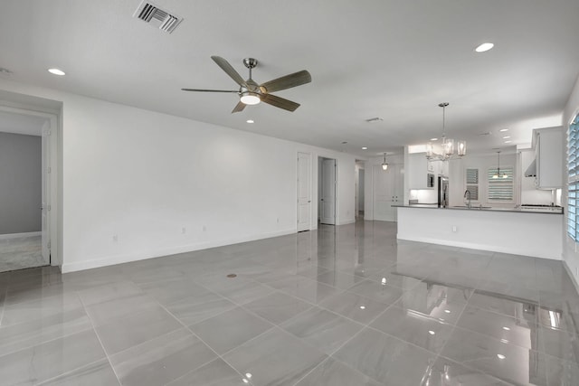 unfurnished living room featuring light tile patterned floors, ceiling fan with notable chandelier, and sink