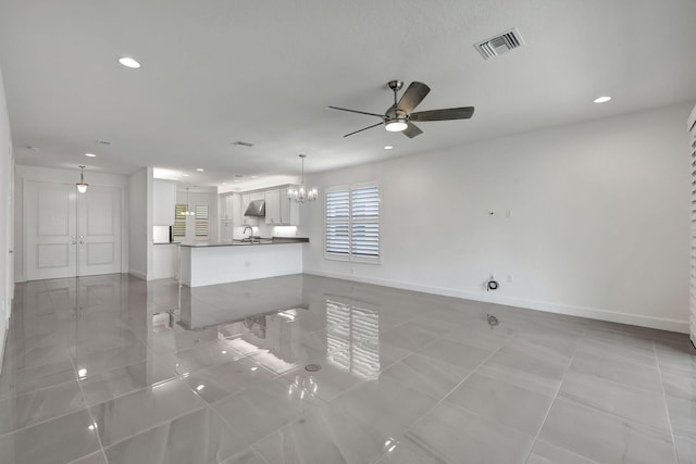 unfurnished living room with light tile patterned floors, ceiling fan with notable chandelier, and sink